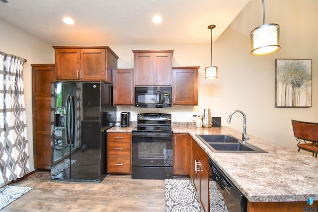5411 S Ledgestone Pl, Sioux Falls, SD 57108 - kitchen featuring black appliances, a sink, a peninsula, light wood-style floors, and hanging light fixtures