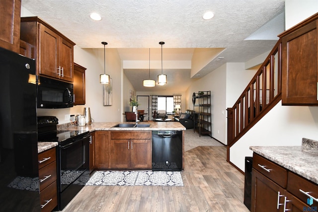 5411 S Ledgestone Pl, Sioux Falls, SD 57108 - kitchen with black appliances, a sink, a peninsula, a textured ceiling, and light wood-type flooring