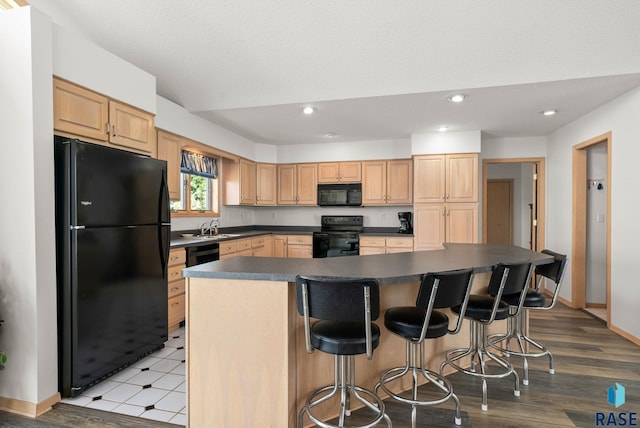 200 Best Point Dr, Madison, SD 57042 - kitchen with black appliances, dark countertops, a sink, recessed lighting, and a breakfast bar area