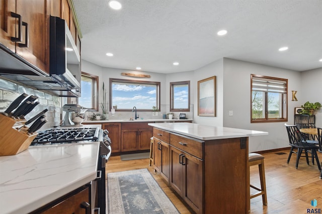 26646 461st Ave, Hartford, SD 57033 - kitchen with a kitchen bar, stainless steel appliances, light wood-style floors, recessed lighting, and light stone counters