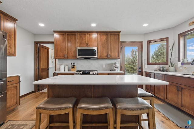 26646 461st Ave, Hartford, SD 57033 - kitchen featuring stainless steel appliances, light wood finished floors, decorative backsplash, recessed lighting, and a kitchen breakfast bar