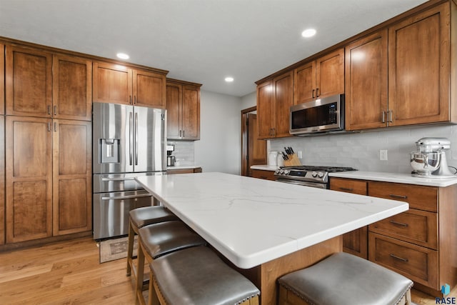 26646 461st Ave, Hartford, SD 57033 - kitchen featuring stainless steel appliances, light wood-style flooring, brown cabinetry, tasteful backsplash, and recessed lighting