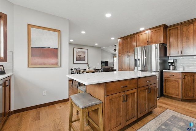 26646 461st Ave, Hartford, SD 57033 - kitchen with stainless steel fridge, light wood-style floors, tasteful backsplash, recessed lighting, and a kitchen breakfast bar