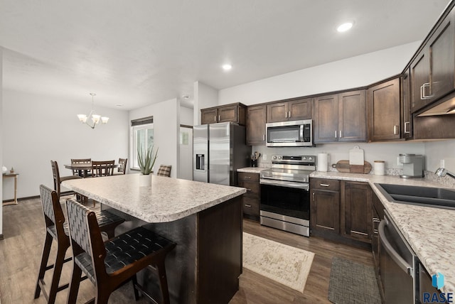 9054 W Ark Pl, Sioux Falls, SD 57106 - kitchen featuring appliances with stainless steel finishes, a sink, dark brown cabinetry, a breakfast bar area, and a kitchen island