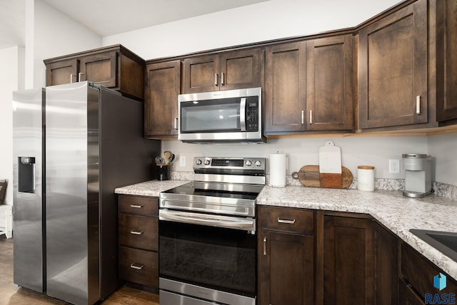 9054 W Ark Pl, Sioux Falls, SD 57106 - kitchen with appliances with stainless steel finishes, dark brown cabinetry, wood finished floors, and light stone counters