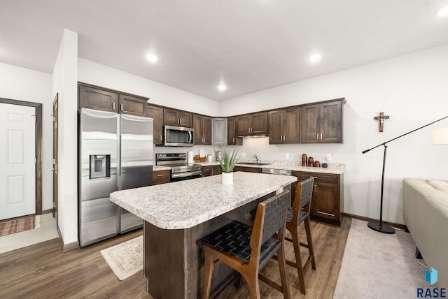 9054 W Ark Pl, Sioux Falls, SD 57106 - kitchen with stainless steel appliances, a sink, dark brown cabinetry, light countertops, and a center island