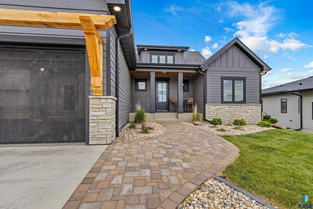 7324 E Twin Pines Ct, Sioux Falls, SD 57110 - view of front of property with stone siding, board and batten siding, a front lawn, and driveway