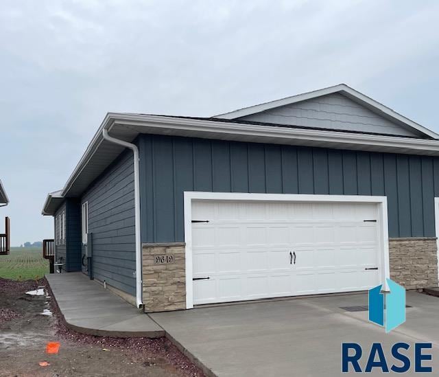 9649 W Tunis Dr, Sioux Falls, SD 57106 - view of side of home featuring stone siding, driveway, and board and batten siding