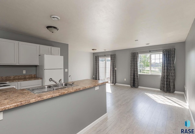6501 S Santa Rosa Pl, Sioux Falls, SD 57108 - kitchen featuring freestanding refrigerator, a sink, baseboards, light wood finished floors, and white cabinetry