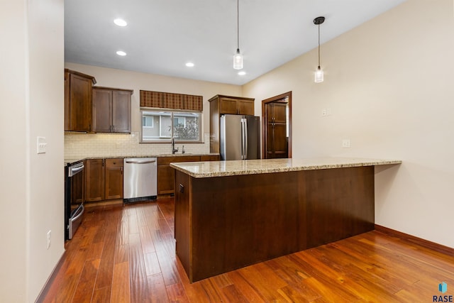 301 S Spring Pl, Brandon, SD 57005 - kitchen with appliances with stainless steel finishes, a peninsula, dark wood finished floors, backsplash, and light stone countertops