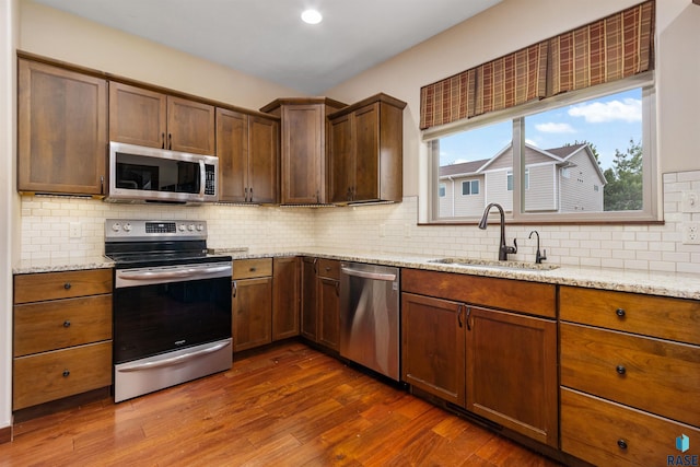 301 S Spring Pl, Brandon, SD 57005 - kitchen with appliances with stainless steel finishes, a sink, tasteful backsplash, dark wood-style flooring, and light stone countertops