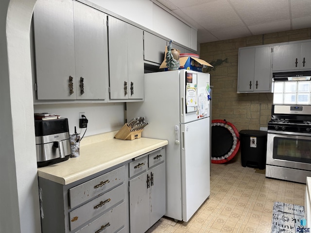 208 E Washington St, Marion, SD 57043 - kitchen with stainless steel range with gas stovetop, gray cabinetry, under cabinet range hood, freestanding refrigerator, and light countertops