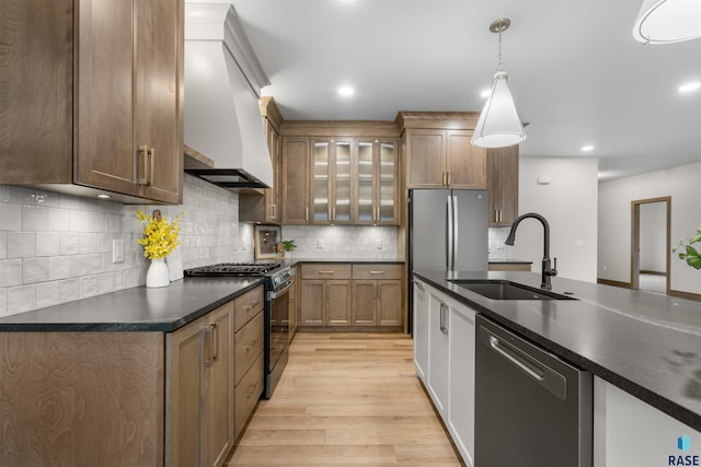 7309 E Shadow Pine Cir, Sioux Falls, SD 57110 - kitchen with appliances with stainless steel finishes, a sink, custom range hood, light wood-style flooring, and dark countertops