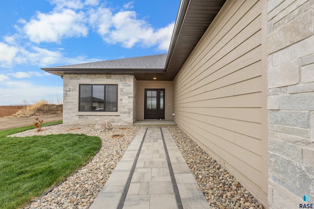 7309 E Shadow Pine Cir, Sioux Falls, SD 57110 - property entrance featuring a shingled roof, stone siding, and a yard