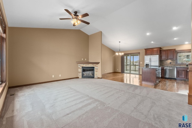 7005 E Archstone St, Sioux Falls, SD 57110 - unfurnished living room featuring light colored carpet, a ceiling fan, lofted ceiling, a chandelier, and a stone fireplace