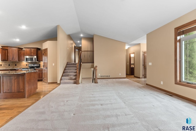 7005 E Archstone St, Sioux Falls, SD 57110 - kitchen featuring stainless steel appliances, lofted ceiling, light colored carpet, baseboards, and decorative backsplash