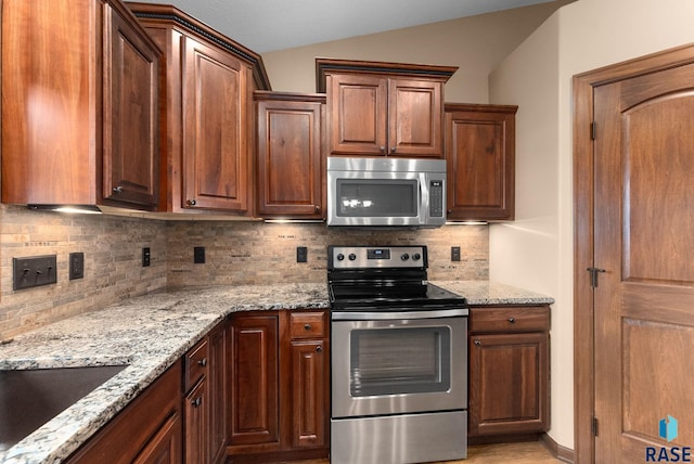 7005 E Archstone St, Sioux Falls, SD 57110 - kitchen with appliances with stainless steel finishes, tasteful backsplash, light stone countertops, and lofted ceiling
