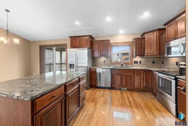 7005 E Archstone St, Sioux Falls, SD 57110 - kitchen with stainless steel appliances, a sink, light wood-type flooring, decorative backsplash, and dark stone countertops
