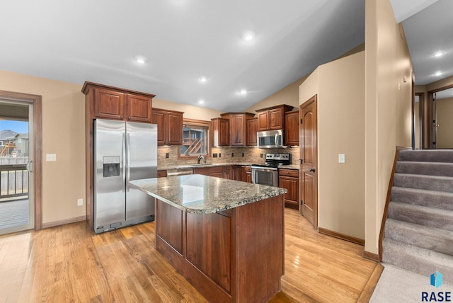 7005 E Archstone St, Sioux Falls, SD 57110 - kitchen featuring stainless steel appliances, light wood-style floors, decorative backsplash, stone countertops, and lofted ceiling