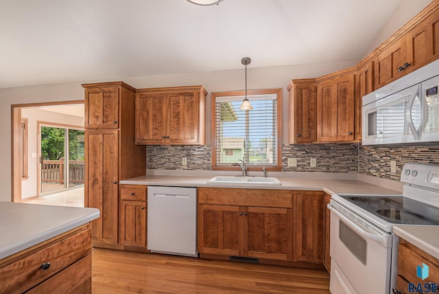 5547 S Wexford Ct, Sioux Falls, SD 57106 - kitchen featuring white appliances, a sink, tasteful backsplash, light wood finished floors, and brown cabinetry
