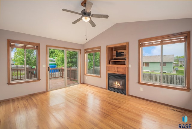 5547 S Wexford Ct, Sioux Falls, SD 57106 - unfurnished living room with wood finished floors, a glass covered fireplace, vaulted ceiling, baseboards, and ceiling fan
