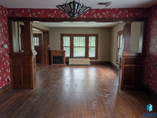 302 E 19th St, Sioux Falls, SD 57105 - unfurnished living room featuring radiator heating unit, ornate columns, wood finished floors, wallpapered walls, and baseboards