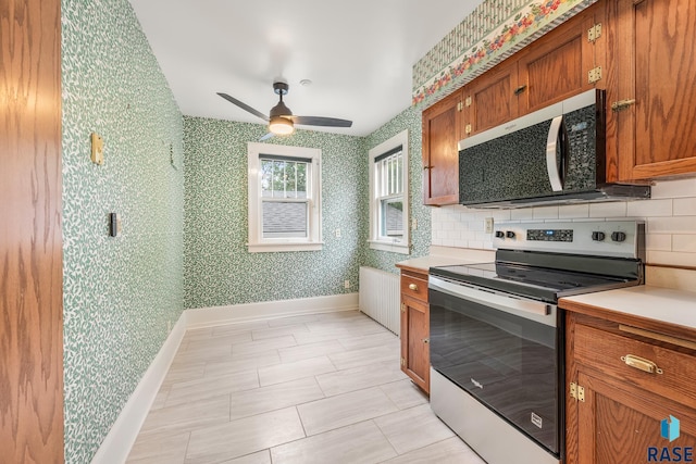 302 E 19th St, Sioux Falls, SD 57105 - kitchen with stainless steel range with electric stovetop, brown cabinets, light countertops, backsplash, and wallpapered walls