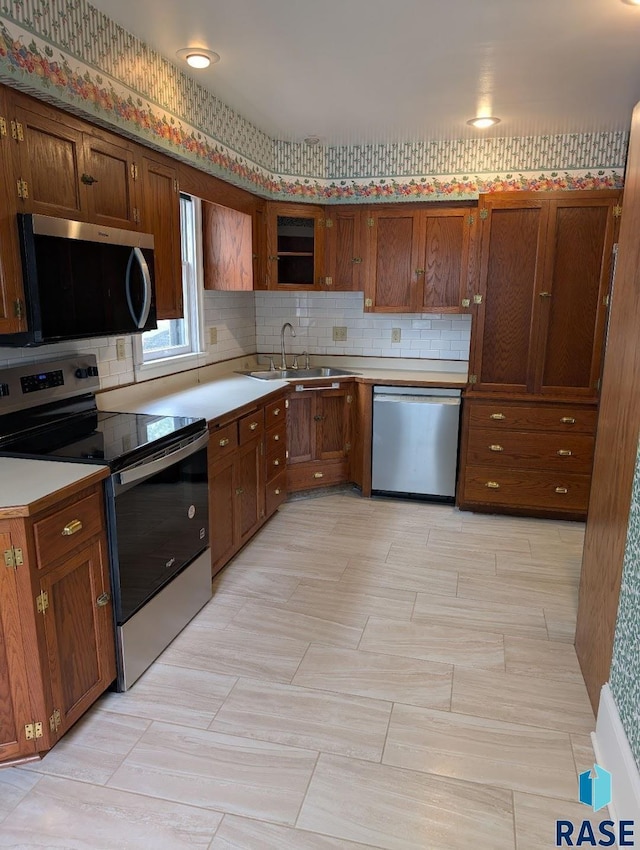 302 E 19th St, Sioux Falls, SD 57105 - kitchen featuring stainless steel appliances, a sink, light countertops, backsplash, and brown cabinets