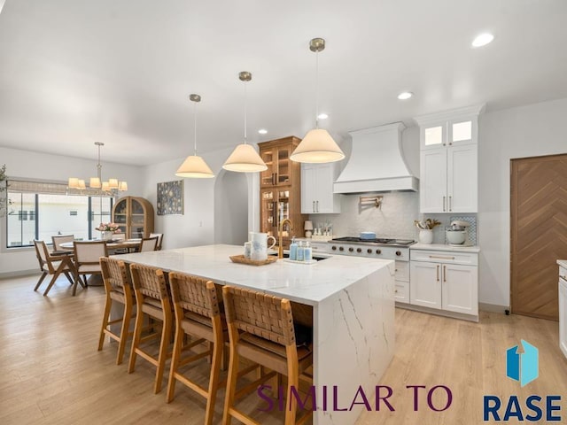 1112 N Slate Ave, Brandon, SD 57005 - kitchen featuring custom exhaust hood, gas cooktop, an island with sink, a chandelier, and white cabinetry