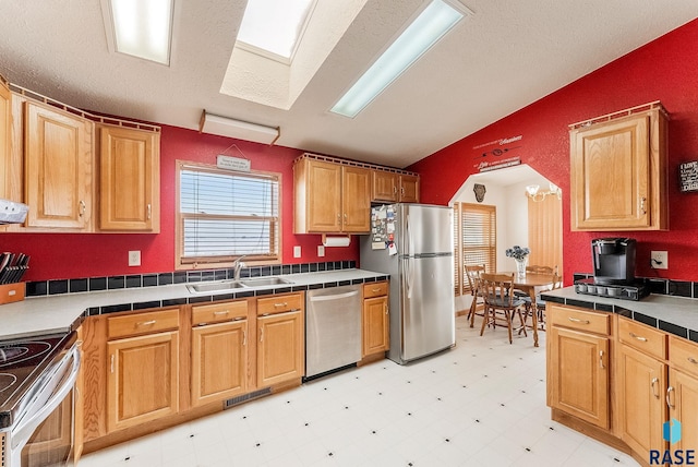 27549 475th Ave, Worthing, SD 57077 - kitchen with appliances with stainless steel finishes, a sink, light floors, vaulted ceiling, and tile counters