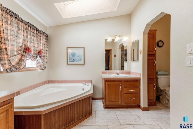 27549 475th Ave, Worthing, SD 57077 - bathroom featuring a skylight, vanity, a bath, toilet, and vaulted ceiling