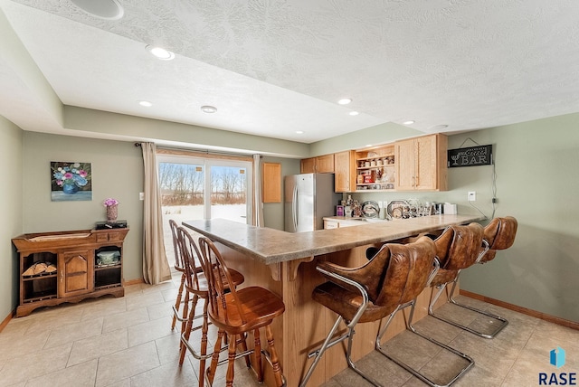 27549 475th Ave, Worthing, SD 57077 - kitchen with freestanding refrigerator, baseboards, a peninsula, a breakfast bar, and open shelves