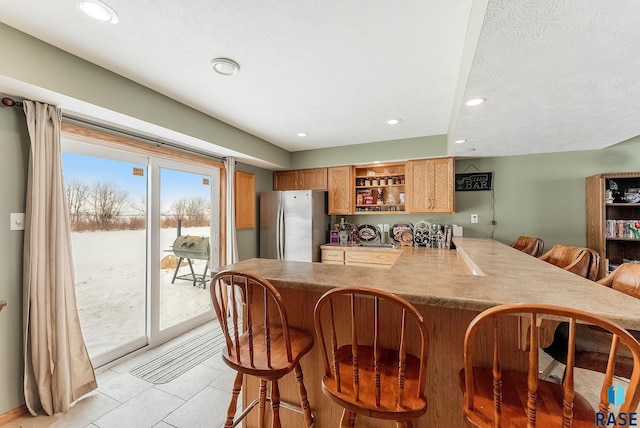 27549 475th Ave, Worthing, SD 57077 - kitchen featuring freestanding refrigerator, a kitchen bar, open shelves, recessed lighting, and light tile patterned flooring