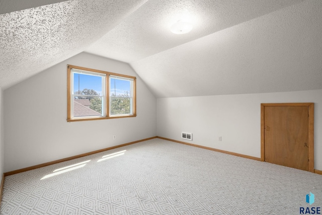1422 E 17th St, Sioux Falls, SD 57104 - additional living space featuring baseboards, lofted ceiling, carpet flooring, and a textured ceiling