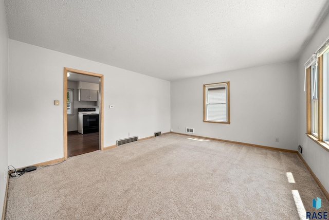 1422 E 17th St, Sioux Falls, SD 57104 - carpeted empty room featuring plenty of natural light, a textured ceiling, and baseboards