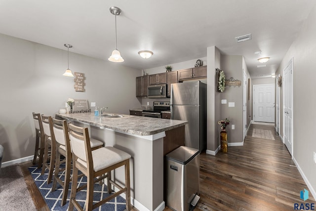 872 S Sycamore Ave Unit 3, Sioux Falls, SD 57110 - kitchen with stainless steel appliances, a peninsula, a sink, a kitchen breakfast bar, and dark wood-style floors