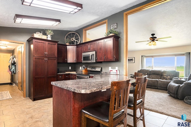 46687 276th St, Lennox, SD 57039 - kitchen featuring electric range, stainless steel microwave, a textured ceiling, open floor plan, and a peninsula