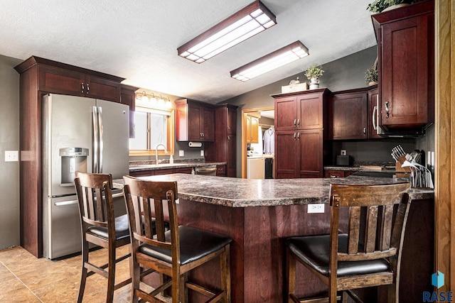 46687 276th St, Lennox, SD 57039 - kitchen with appliances with stainless steel finishes, vaulted ceiling, a sink, a peninsula, and washer / clothes dryer