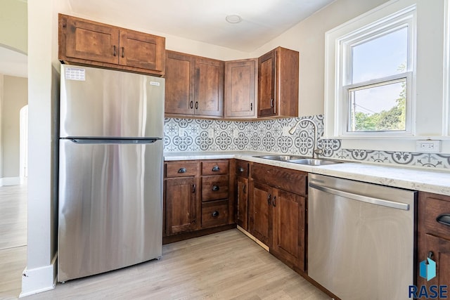 1700 E 7th St, Sioux Falls, SD 57103 - kitchen featuring appliances with stainless steel finishes, light wood finished floors, a sink, arched walkways, and backsplash