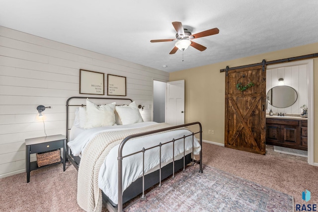1913 S Haraldson Ave, Sioux Falls, SD 57106 - carpeted bedroom with a barn door, baseboards, a sink, wood walls, and ensuite bathroom