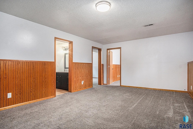 905 S Suburban Dr, Sioux Falls, SD 57110 - empty room featuring wainscoting, a textured ceiling, carpet floors, and wooden walls