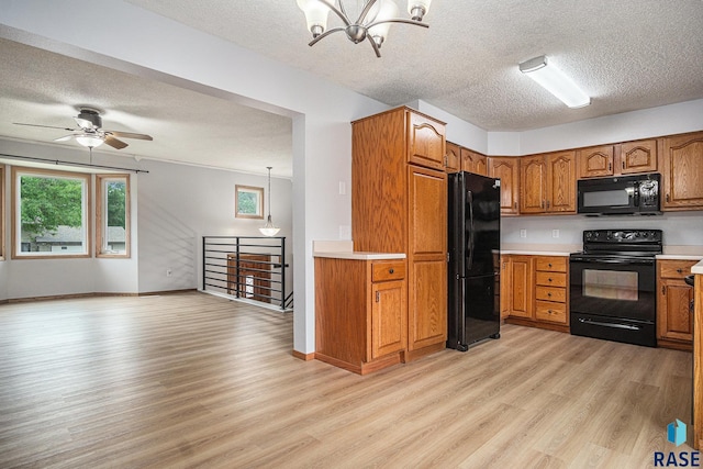 905 S Suburban Dr, Sioux Falls, SD 57110 - kitchen with black appliances, a textured ceiling, light wood-style flooring, a chandelier, and brown cabinetry
