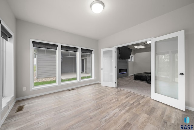 9001 W Rathburn St, Sioux Falls, SD 57103 - unfurnished room with a fireplace, light wood-type flooring, baseboards, and french doors