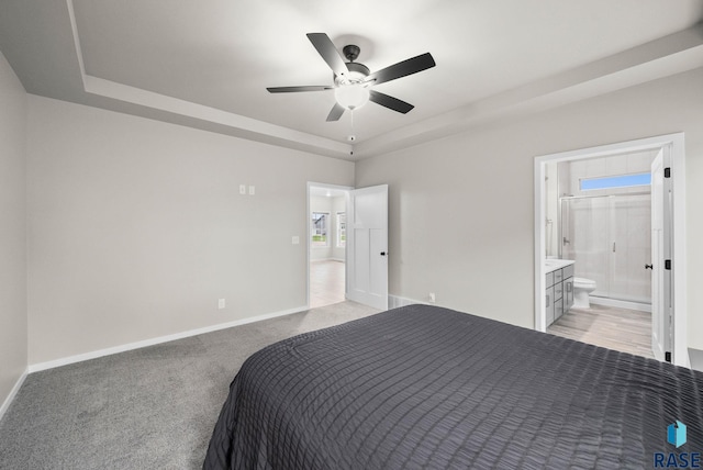 9001 W Rathburn St, Sioux Falls, SD 57103 - bedroom with a raised ceiling, light colored carpet, baseboards, connected bathroom, and ceiling fan
