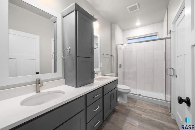9001 W Rathburn St, Sioux Falls, SD 57103 - bathroom with double vanity, toilet, a stall shower, and wood finished floors