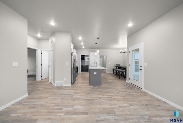 9001 W Rathburn St, Sioux Falls, SD 57103 - kitchen with stainless steel fridge with ice dispenser, a sink, white cabinets, a center island with sink, and a chandelier