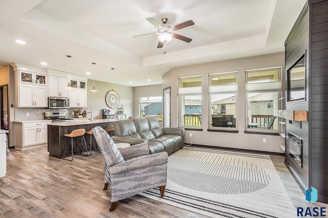 2604 S Ronell Cir, Sioux Falls, SD 57106 - living area featuring a raised ceiling, light wood-style floors, a ceiling fan, and recessed lighting