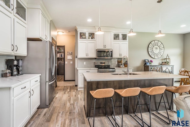 2604 S Ronell Cir, Sioux Falls, SD 57106 - kitchen featuring appliances with stainless steel finishes, a sink, a breakfast bar, decorative backsplash, and light wood-style flooring