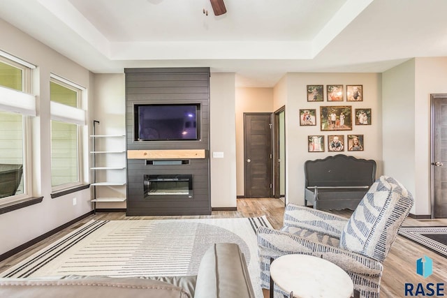 2604 S Ronell Cir, Sioux Falls, SD 57106 - living area with a raised ceiling, wood finished floors, a fireplace, a ceiling fan, and baseboards
