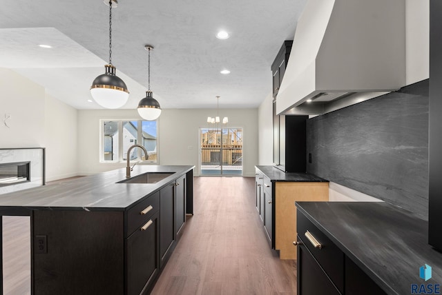8309 E Sheridan Cir, Sioux Falls, SD 57110 - kitchen with a sink, custom exhaust hood, light wood-style floors, a chandelier, and pendant lighting